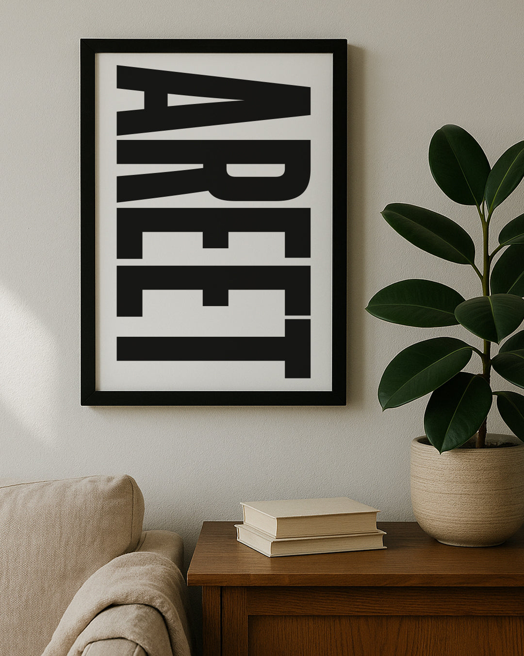 Framed vertical typography print featuring the word "AREET" in bold black capital letters on a white background. Displayed on a wooden table next to a large green rubber plant. Designed for Geordie Gifts.
