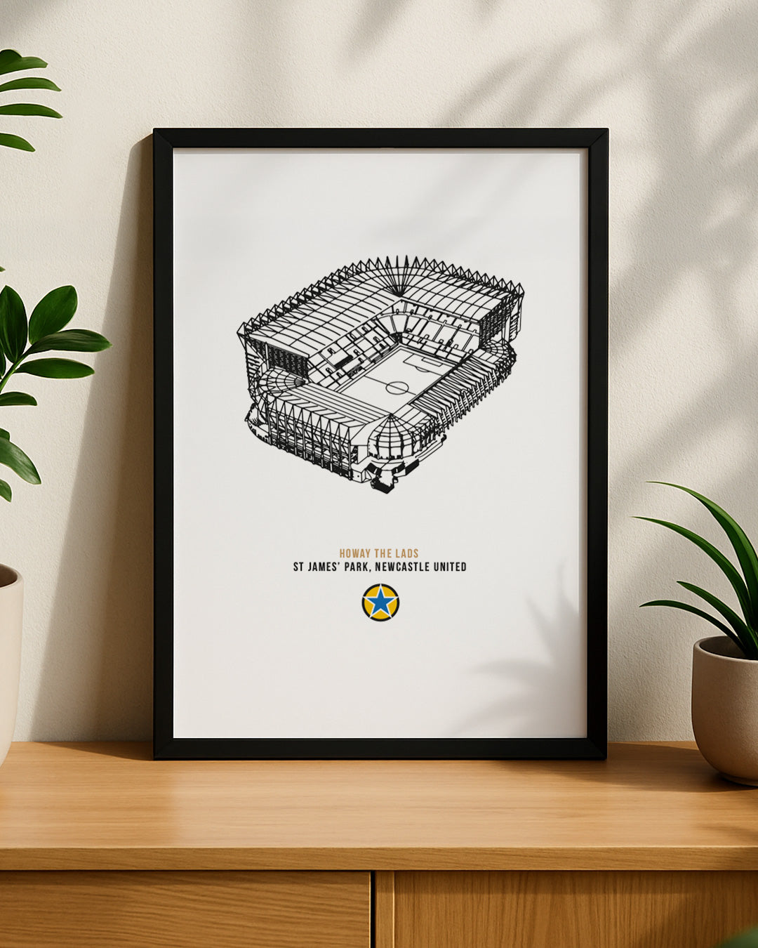 A minimalist black-framed illustration of the Newcastle United football ground sitting on a wooden sideboard.