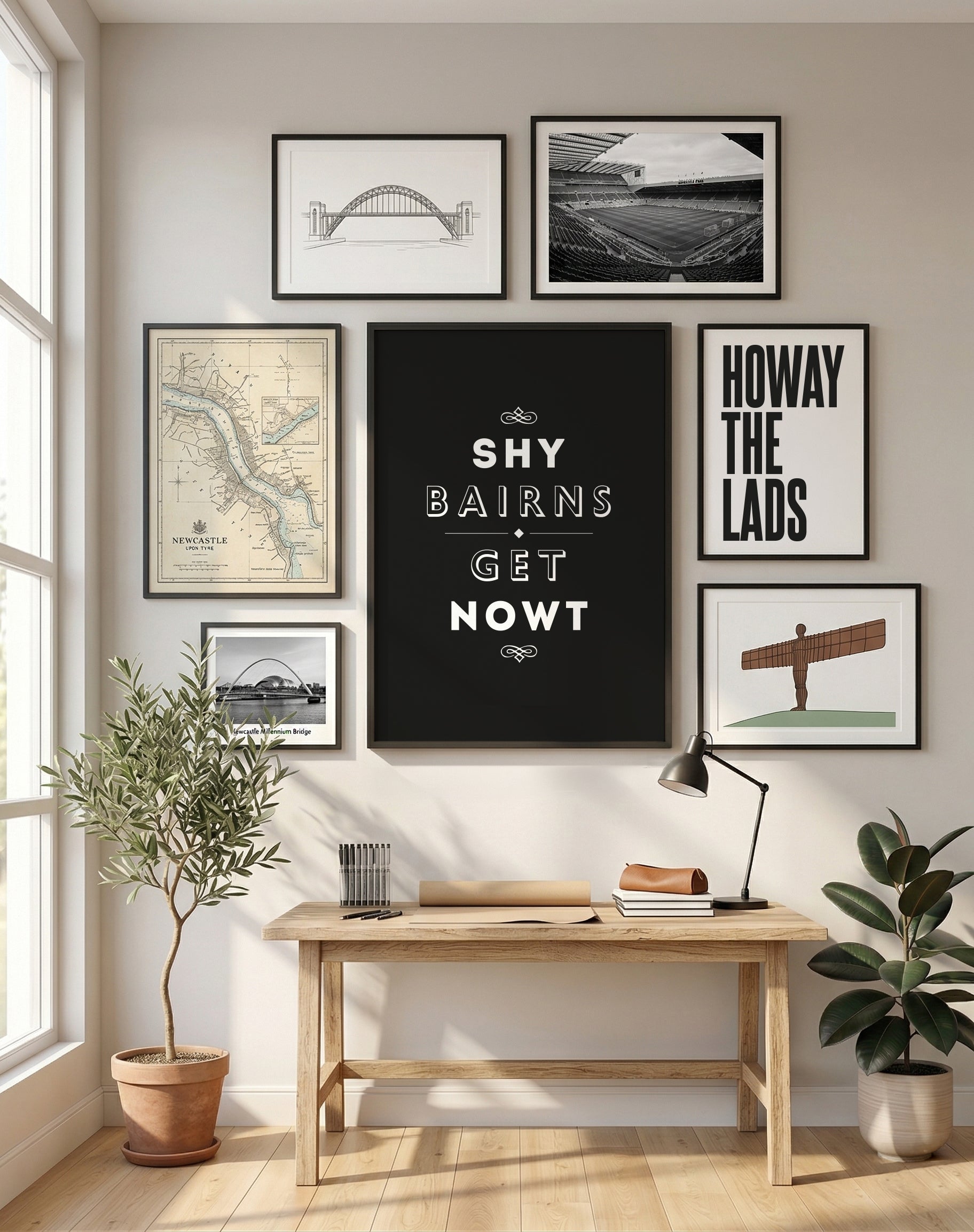 A black 'Shy Bairns Get Nowt' framed print on a wooden desk with a lamp and stationery.
