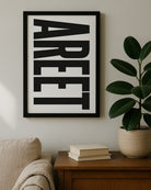 Framed vertical typography print featuring the word "AREET" in bold black capital letters on a white background. Displayed on a wooden table next to a large green rubber plant. Designed for Geordie Gifts.