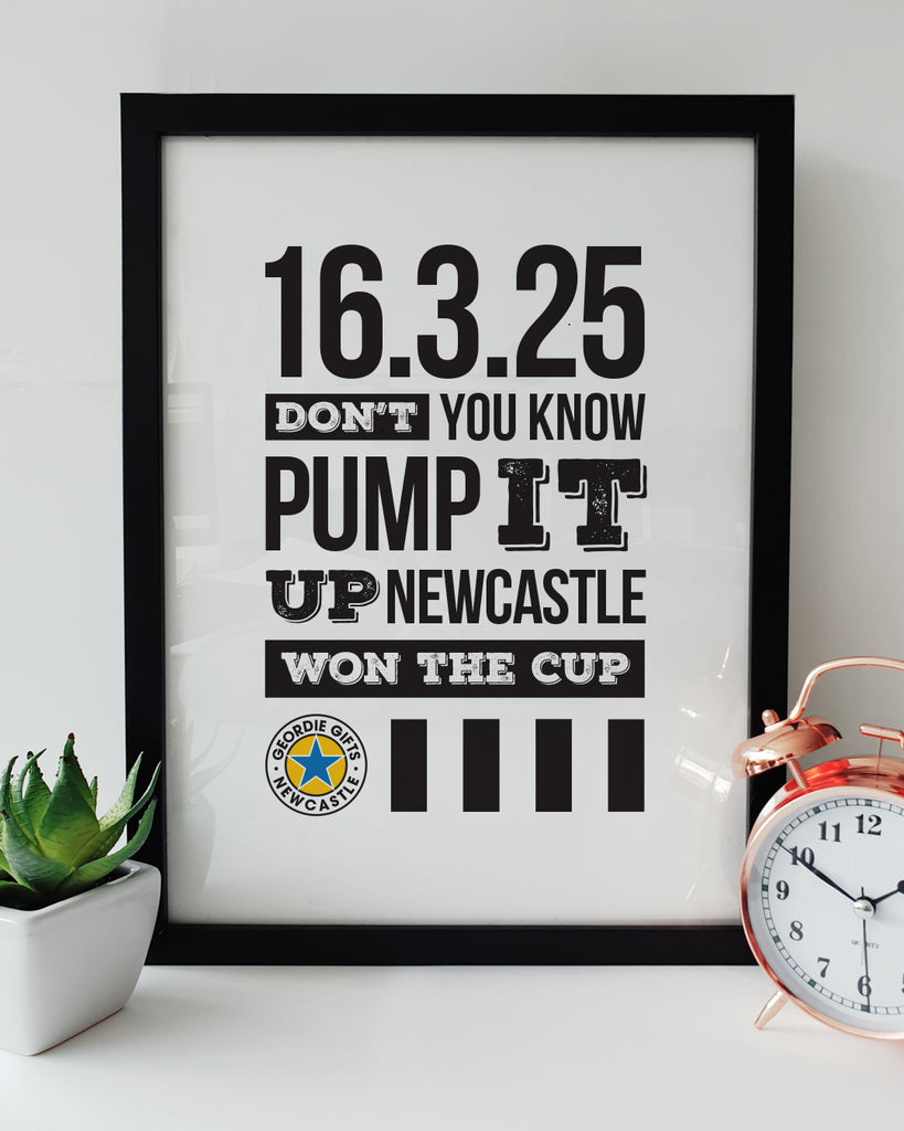 Geordie Gifts Newcastle United print for supporters, featuring a typographic design with the ‘Pump It Up’ chant and the 2025 Carabao Cup final victory date 16.3.25, displayed in a black frame with a plant and clock.