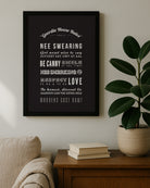 Framed black typography print featuring "Geordie Hoose Rules" in white vintage lettering. Displayed on a wooden table next to a large green rubber plant. Rules include "Nee swearing" and "Manners cost nowt". Designed for Geordie Gifts.