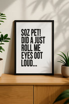 Black framed funny Newcastle quote print reading "Soz Pet! Did A Just Roll Me Eyes Oot Loud..." styled on a wooden sideboard. designed by geordie gifts