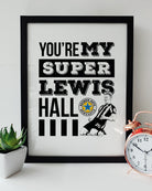 Black framed "You're My Super Lewis Hall" Newcastle United chant print featuring Lewis Hall goal celebration illustration by Geordie Gifts next to a rose gold alarm clock.   