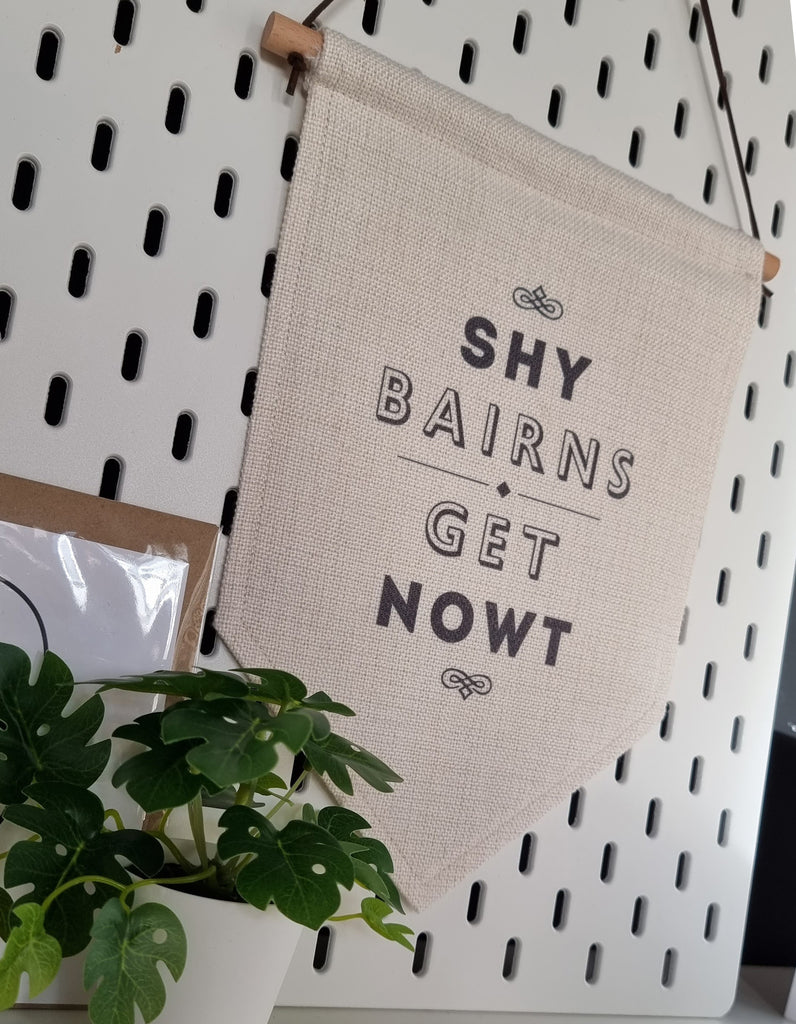 SHY BAIRNS GET NOWT POPULAR GEORDIE AND NEWCASTLE QUOTE AND PHRASE PRINTED ON A HANGING SIGN LINE FLAG. PERFECT HOMEWARE AND DESIGN FOR A NORTHEAST HOME (HYEM)